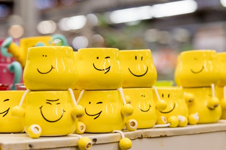 A lot of yellow cups with funny faces on blurred background. The concept of a friendly company, a big family, meeting friends for a cup of tea or coffee, fathers day, office, boss day.Friendship day celebration.April Fools Dayの写真素材