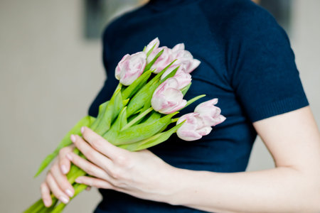 florist woman holding a beautiful colourful blossoming flower bouquet of fresh white pink tulips,...