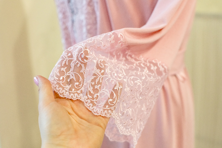 Silk pink women peignoir on yellow background. Fashion women underwear. Satin Womens nightgown. fashionable lingerie.Sexy pastel colored negligee. Lace robe is expensive and translucent.の写真素材