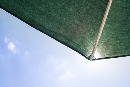 Patio umbrella against blue sky with clouds in the summer.Protection from the sun, concept. Copy...
