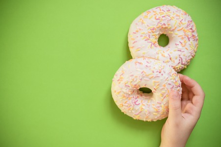 child holds in hand colorful white donut isolated.Proper nutrition or sweets, dessert fast food, dieting morning concept. Copy space for advertisement. Advertising area. tasty vanilla donut with sprinkleの写真素材