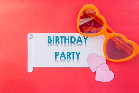 orange heart shaped glasses isolated on red background.Birthday party concept. Funny sunny glasses on red background, heart symbol. Summer beach eventの写真素材