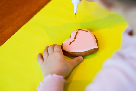 woman confectioner decorates and decorates the glaze with gingerbread cookies in the shape of heart. Valentine's Day, February 14, symbol, valentine, gift.の写真素材