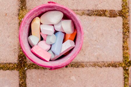 A bucket of colorful chalk on the asphalt in plastic box. Drawing with chalk on the pavement.multicolored crayons for drawing.の写真素材