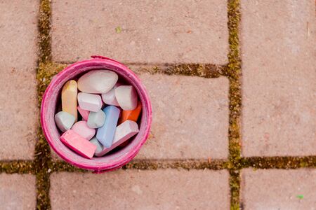 A bucket of colorful chalk on the asphalt in plastic box. Drawing with chalk on the pavement.multicolored crayons for drawing.の写真素材