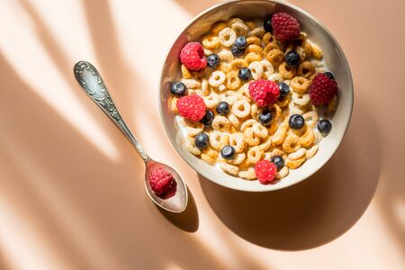 Tasty cornflakes with raspberries and blueberries on pink backgroundの写真素材