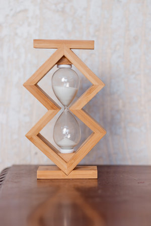 Close up of hourglass clock on a wooden floor with copy space. Hourglass time passing concept for...