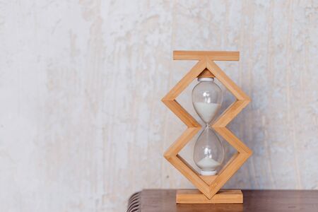Close up of hourglass clock on a wooden floor with copy space. Hourglass time passing concept for business deadline, urgency and running out of time.Time abstraction.wooden Hourglass.Copy spaceの写真素材