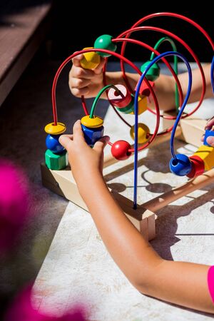 Children Educational toy maze.little girl playing with educational toy - labyrinth. kindergarten concept, lifestyle. Early education and development.Game Toy toddler blocks. Colorful wooden toysの写真素材
