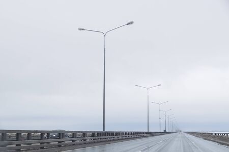 Dark highway in cloudy weather after rain.straight way with dramatic clouds. empty highway, cloudy sky, lighting on the road. Travel in any weather.の写真素材