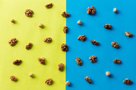Walnut kernel pattern backdrop. One open nut shell with kernel on yellow blue background. Top view.Flat lay composition with Different types of nuts on colorful background.nut textures and surface with pattern for backgroundの写真素材