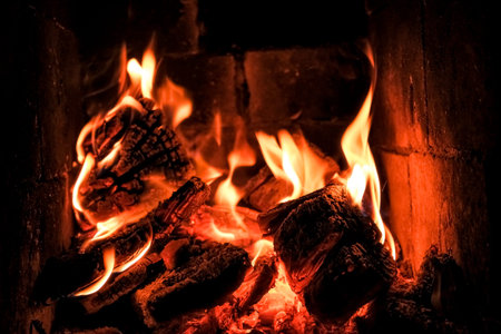 bright flame of fire burns in a fireplace in the old house in winter evening