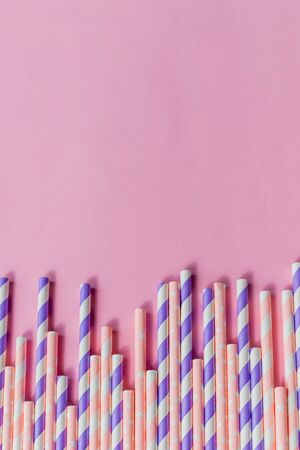 Striped drink straws of different colors in row isolated on yellow background. Minimalism concept. Pop art style. Flat lay with straws. Birthday Party Celebration Kids Fun. Greeting Card Poster Template. Copy Spaceの写真素材