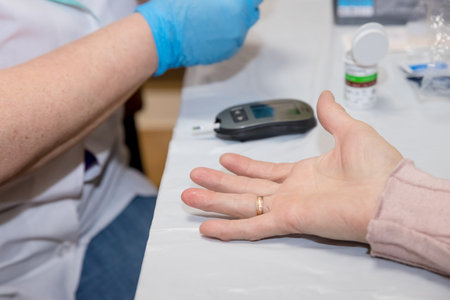 Doctor testing a patients glucose level after pricking his finger to draw a drop of blood and then...