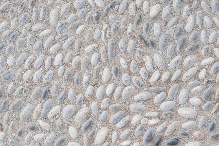White pebble in concrete path. Top view stone background. Seaside pebble photo texture. Stone paving surface. White marbles flat lay background. Natural outdoor decor material.rounded cobbles set into street walkway.の写真素材