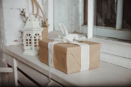 Christmas decor with lantern, box in kraft wrapped paper, gift box lie on the windowsill. Scandinan minimalist interior.の写真素材