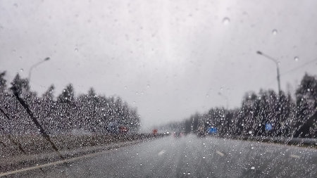 Visibility is limited when driving through a rain storm, raindrops splatter on the windshield of a...