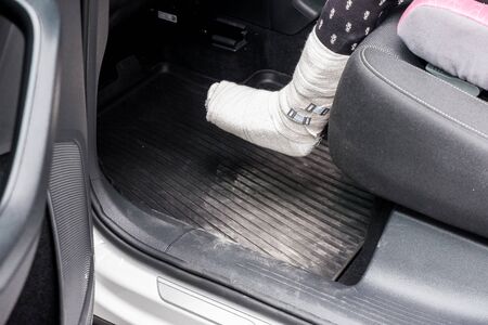 Human healthcare and medicine concept. little child with plaster bandage on leg heel fracture or broken foot bone sitting in car.broken bone, fracture of the ankle. Drive to check up in hospital.copy space. kid after accidentの写真素材