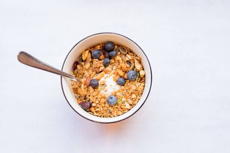 bowl of muesli and yogurt with fresh berries. diet dessert with yogurt, granola and fresh berries, blueberries, care of health. proper diet.Healthy breakfast, yogurt with blueberries, muesli served in bowl on white backgroundの写真素材