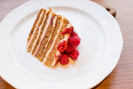 sweet honey cake decorated with raspberry,berries on white plate.fresh cake with red raspberries. Delicious Dessert for tea. fresh Raspberry cake. Homemade berries cake. Copy space. Selective focus.の写真素材
