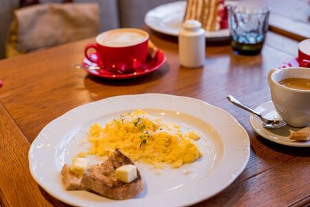 Simple and Delicious Breakfast of Mini Bratwurst Sausages, Eggs Scrambled with Cheese, Toast, and Black Coffeeの写真素材