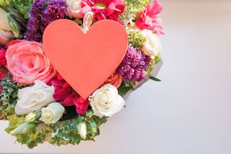Valentine's day elegant bouquet with roses flowers, Lisianthus, chrysanthemum and red wooden heart, sign of love.の写真素材