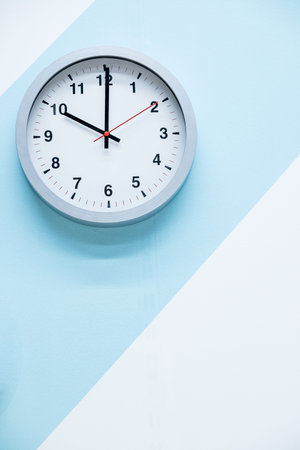 minimalistic white wall clock with light metal on a blue white background. time concept.Theme of...