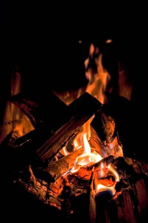 three burning billets in hot stove.Fire flame burning coal and wood in fireplace.Hot coals in the fire.Flames of a campfire in the night.Toned imageの写真素材