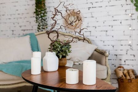 white candles on wooden coffee table in cozy living room interiorの写真素材