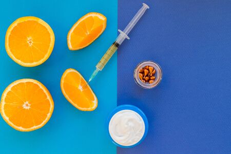 Vitamin C, natural anti aging cosmetics serum and syringe with ornge fruit slices.Cream with oranges on blue background.Natural cosmetics concept.atural beauty product concept.Copy spaceの写真素材