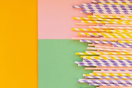 Drinking paper straws on yellow background with copy space. Top view of colored paper disposable eco-friendly straws for summer cocktails.の写真素材