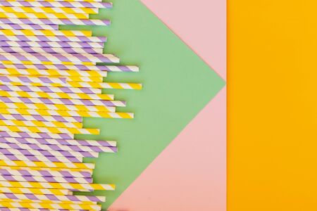 Drinking paper straws on yellow background with copy space. Top view of colored paper disposable eco-friendly straws for summer cocktails.の写真素材