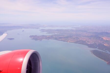 Aerial view of airplane flying above shade clouds and sky. Airplane wing fly over tropical island. View from the plane window of emotional moment during international travel around the world.islands in Thailandの写真素材