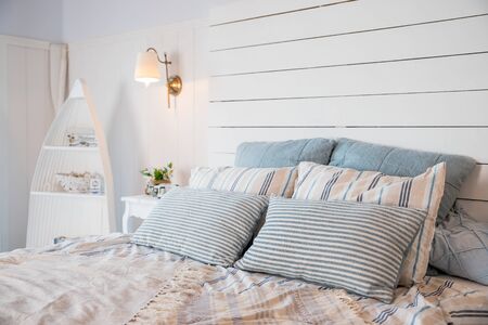 Beige blanket on king-size bed and cacti in gold pots on cupboard in spacious bedroom.King-size bed with soft bedhead and pastel pink bedding.Pastel blanket on bed in bedroom interiorの写真素材