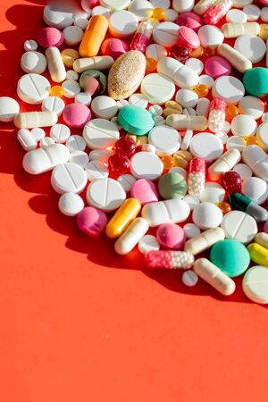 different colorful pills, capsules, tablets on red background. medical healthcare. Pharmaceutical medicine pills, tablets and capsulesの写真素材