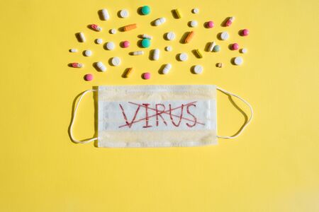 black letters are lined with the word covid, pills with a medical mask. flu, virus.Protective face mask, surgical mask. Coronavirus disease. colorful pills. Top viewの写真素材