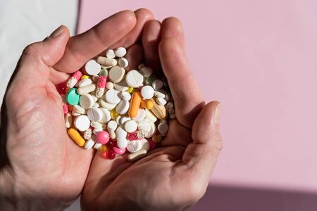 man holding pills on hand.Overdose of medication. A lot of pills spilled on table. Attempt of suicide.Economic crisis and medicine problems. Virus pandemic.Copy spaceの写真素材