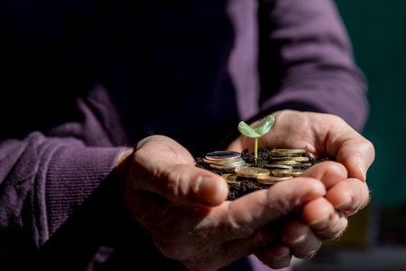 Seedlings are grown on a coin placed on the ground, While a mens hands were surrounded. coins are...