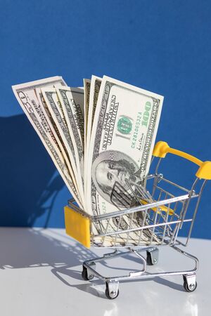 yellow shopping cart and dollar on the blue background , online shopping concept.Creative promotion composition for online shopping sale and grocery cart.の写真素材