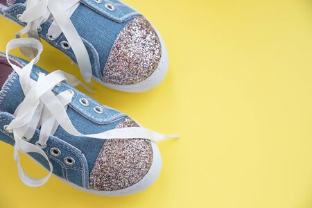 Fashionable blue sneakers for girls isolated on yellow background. Pair of trendy kids sports shoes.Trandy denim sneakers for kids.の写真素材