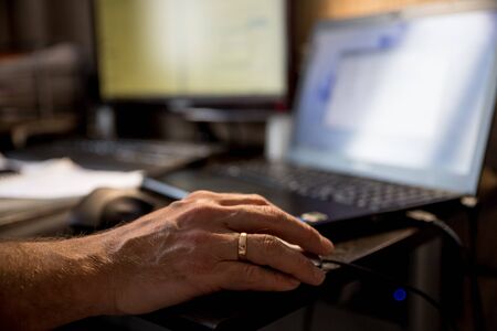 Casual man typing on mobile smart phone while working on laptop computer in coffee shop.の写真素材