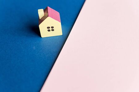 Real estate, house model outdoors, closeup.Wooden model house on a Geometric pink and blue background with copy space.Concept for property ladder, mortgage and real estate investment.の写真素材