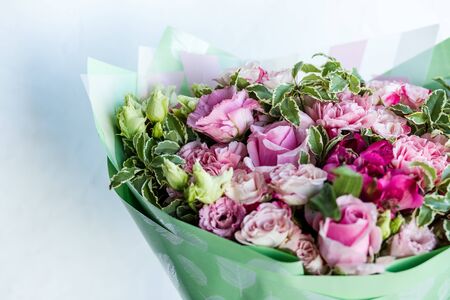 Close-up beautiful luxury bouquet of mixed flowers. the work of the florist at a flower shop. Spring bouquet. Bright bouquet including roses, lisianthus, pink carnation and green leavesの写真素材