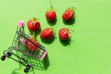 Shopping cart filled with fresh strawberries isolated over whiteの写真素材