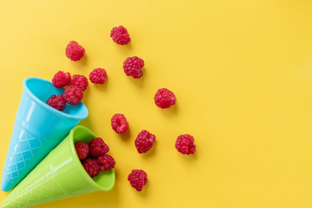 colorful Waffle cone with fresh organic raspberries on bright background. Summer berries,Pop art...