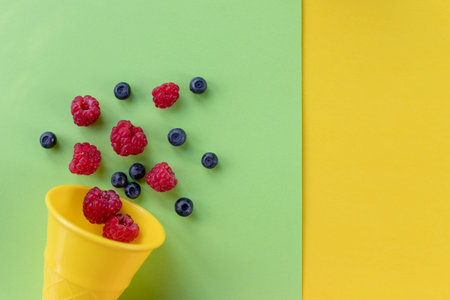 Explosion of different berries. Flat lay with blueberry and raspberry in plastic waffle cone on...