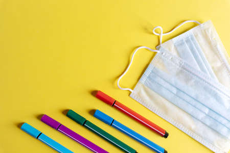protective mask and school supplies on yellow background, concept of new normality for children and protection against viruses, copy space.Back to school conceptの写真素材