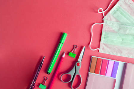 school supplies with medical face mask on red background. Protection of schoolchildren and students from the virus.Education, learning concept.protective medical face mask .pandemic.の写真素材