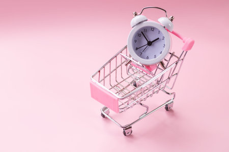 Black friday sale concept. shopping cart and white alarm clock on pink background. Business concept....