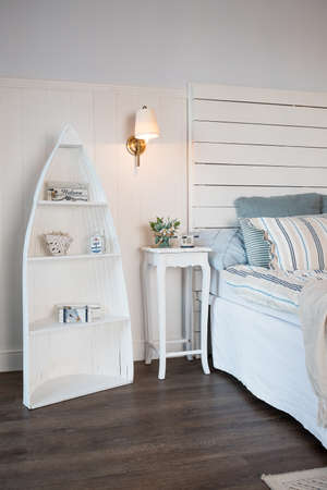 Bright and comfortable bedroom interior design in scandinavian style.Flowers on bedside table. Pillow on bed decoration room interior. Burning small lamp above a table.の写真素材